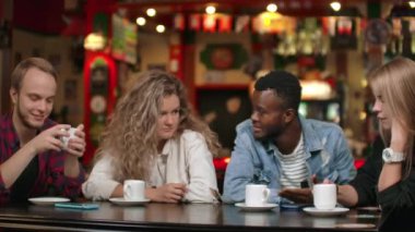 Mutlu çeşitli arkadaşları birlikte akıllı telefonda komik online video izlerken gadget ile eğlenmek, çok kültürlü genç arkadaşlar telefon konuşurken gülen toplantı da mobil uygulamalar kullanın masada oturun.