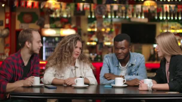 Une multinationale d'amis boit du café et parle dans un restaurant. Quatre amis bavardant . — Video