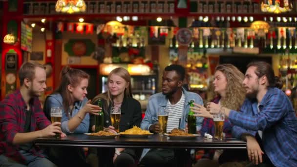 Afroamerikaner mit Freunden an einer Bar, trinkt Bier und isst Chips mit Freunden — Stockvideo