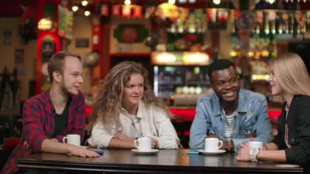 Een multinationale gezelschap van vrienden koffie drinken en praten in een restaurant. — Stockvideo