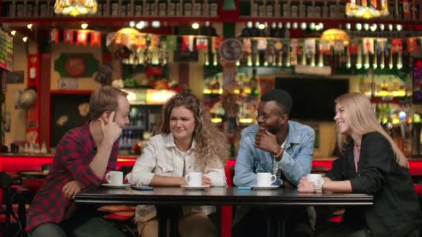 Χαρούμενη πολυεθνική παρέα φίλων σε ένα εστιατόριο πίνοντας καφέ μιλώντας και συζητώντας αφηγήσεις ιστορίες για το Πανεπιστήμιο θυμούνται αστείες στιγμές — Αρχείο Βίντεο