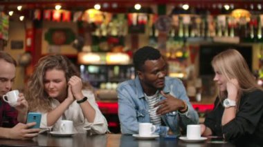 Bir arkadaş şirketinde komik hikayeler anlat. Çokuluslu erkek ve kadın kahve fincanları ile bir masada birlikte oturan
