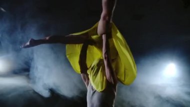 İki dansçı bir erkek ve bir kadın birbirlerine koşmak ve bir erkek ortağı kollarında sarı bir elbise bir kadın yükseltir ve havada en iyi destek performans döner