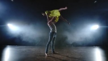Zoom kamera, iki modern bale dansçısı sahnede duman dans eden bir adam kollarında ortağını yükseltir ve havada döner. Müzikal sirk akrobatlar dansçılar kullanır