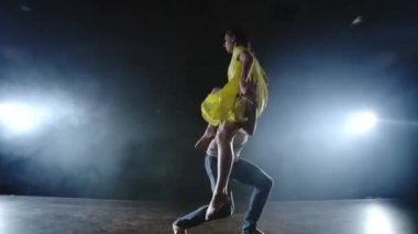 Zoom kamera, iki modern bale dansçısı sahnede duman dans eden bir adam kollarında ortağını yükseltir ve havada döner. Müzikal sirk akrobatlar dansçılar kullanır