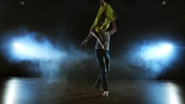İki dansçı bir erkek ve bir kadın birbirlerine koşmak ve bir erkek ortağı kollarında sarı bir elbise bir kadın yükseltir ve havada en iyi destek performans döner
