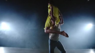 Zoom kamera, bir kadın dansçı ortağı omzuna atlar. Sahnede duman halinde akrobatik dans müzikali. Çağdaş Contemp