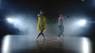 Kamerayı yakınlaştırın. Modern romantik koreografi. Aşk sahnede. Bir erkek ve bir kadın birlikte kot pantolon komik bir dans ve duman sahnede sarı bir elbise dans. Müzikal