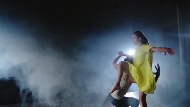 Zoom-Kamera tanzen zwei moderne Balletttänzer in Rauch auf der Bühne, ein Mann hebt seine Partnerin in die Arme und dreht sich in der Luft. Das Musical verwendet Zirkusakrobaten Tänzer — Stockvideo