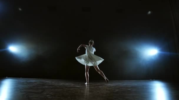 Zoom camera moves around the stage with software and smoke. Girl ballerina dancing in a white dress spinning plastic while performing pirouettes and rotations, experiencing emotions — Stock Video