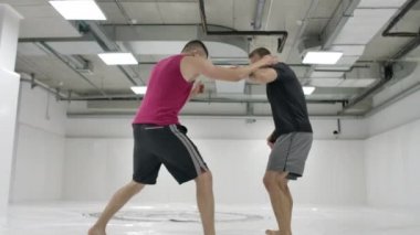 Erkek güreşçilerden sonra kamera hareket eder. Mma dövüşçüleri antrenman pistlerinde güreş ekipmanları üzerinde çalışırlar. Yakalama, atar ve acı hamle