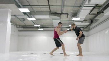 Beyaz bir odada iki erkek güreşçi paspas atma dışarı çalışır. Bir kıskaç al ve kendini at.