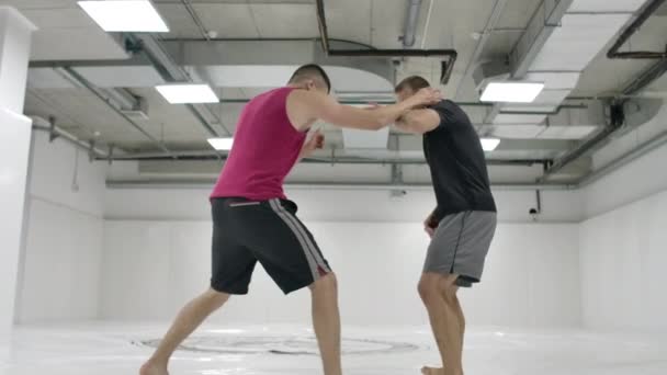 The camera moves after the men wrestlers. MMA fighters work out wrestling equipment on training tracks. Capturing, throws and painful moves — Stock Video