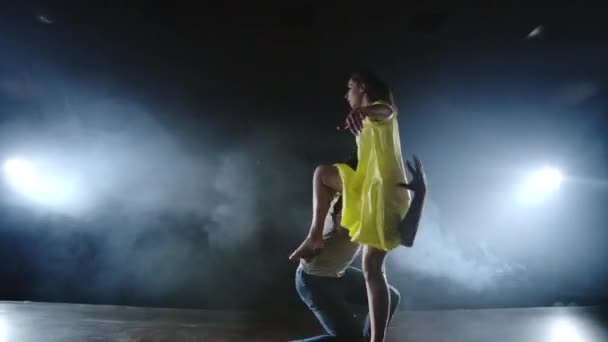 Два танцора мужчина и женщина бегут друг к другу, а мужчина-партнер поднимает женщину в жёлтом платье на руках и вращается в воздухе, выполняя верхнюю поддержку. — стоковое видео