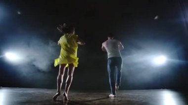Kamerayı yakınlaştırın. Modern romantik koreografi. Aşk sahnede. Bir erkek ve bir kadın birlikte kot pantolon komik bir dans ve duman sahnede sarı bir elbise dans. Müzikal