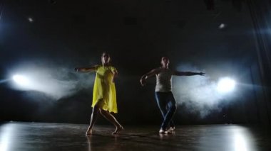Kamerayı yakınlaştırın. Modern romantik koreografi. Aşk sahnede. Bir erkek ve bir kadın birlikte kot pantolon komik bir dans ve duman sahnede sarı bir elbise dans. Müzikal