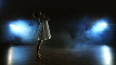 Beyaz elbiseli bir kadın sahnede modern balenin dramatik dansları dans ediyor. Bir bale dansçısı duman modern koreografi performans plastik taşır