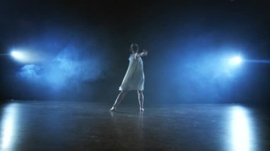 Beyaz kısa elbiseli modern kız dansçı plastik güzel dramatik danslar gerçekleştirir, sahne boyunca çalışan, yere düşen ve iplik. Fenerler ve duman