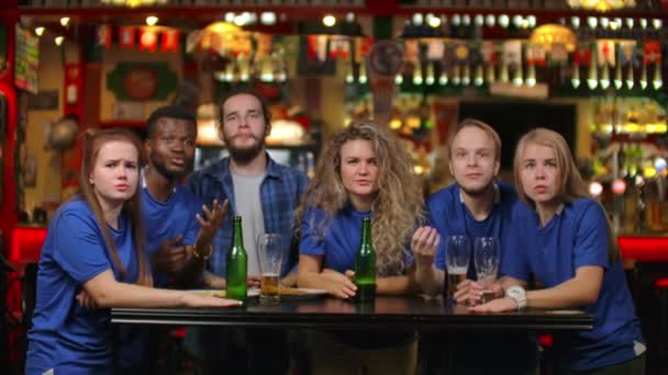 Ventiladores emocionais com camisas azuis num bar de cerveja. Um grupo multi-étnico de afro-americanos estão chateados e tristes por causa do fracasso de sua equipe. Derrota do seu futebol favorito, voleibol , — Vídeo de Stock
