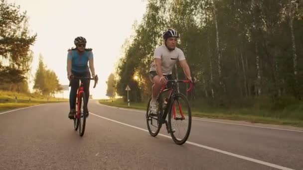 Hard Training.Triatleta due ciclista formazione su bicicletta da strada. due ciclisti in sella alla bici da strada nel parco cittadino e si preparano per il triathlon.Fit atleta di formazione intensiva due uomini e donne in bicicletta — Video Stock