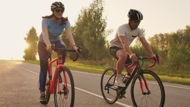 Steadicam tiro de dos mem saludable y mujer que pedalea rápido con bicicleta de ciclismo de carretera al atardecer . — Vídeo de stock