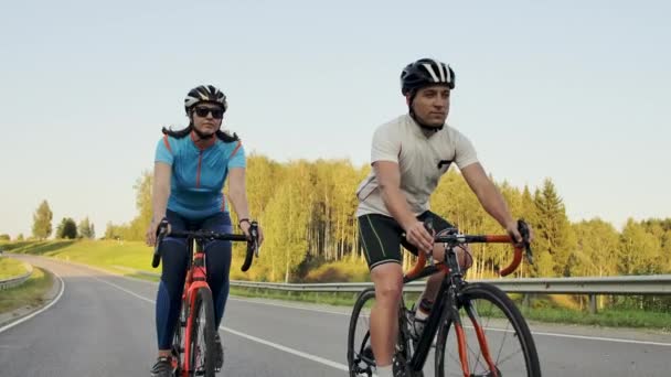 Steadicam schot van fietsen paar berg rijden op fietsweg bij zonsondergang doen hoge — Stockvideo