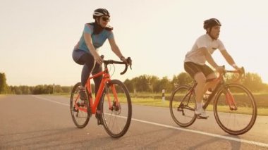 Gün batımında bisiklet yol bisikleti ile hızlı satarak iki sağlıklı mem ve kadın Steadicam çekim.
