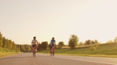 Sert Eğitim.Triathlete iki Bisikletçi Eğitim Yol Bisiklet i. Iki Bisikletçi City Park'ta Yol Bisikleti Üzerinde Sürme ve Triatlon.Fit Atlet Yoğun Eğitim iki erkek ve kadın Bisiklet için hazırlanıyor