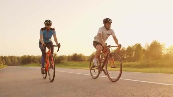 Kemény edzés. triathlete két kerékpáros képzés a közúti kerékpár. két kerékpáros Riding a közúti Bike a városi parkban, és felkészülnek a triatlon. Fit sportoló intenzív edzés két férfi és nő kerékpározás — Stock videók