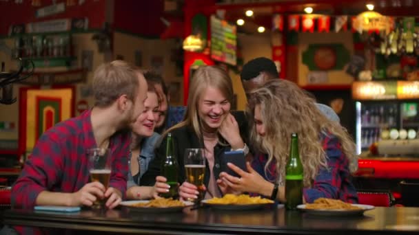 Un grande gruppo di amici al bar seduti a tavola ridono e chiacchierano bevendo birra — Video Stock