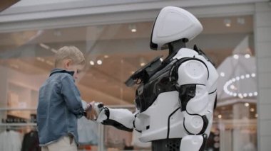 çocuk bir el sıkışma için robota elini uzatır.