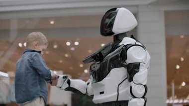 çocuk bir el sıkışma için robota elini uzatır.