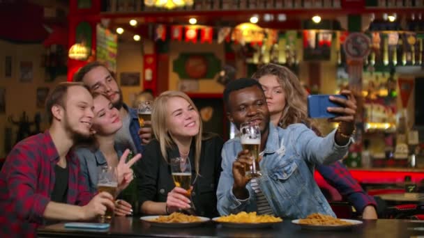 Freunde machen Selfie mit Smartphone in Bar. Junge Leute posieren, lachen und reden. Bierflaschen und. Freunde machen Selfie mit Smartphone. — Stockvideo