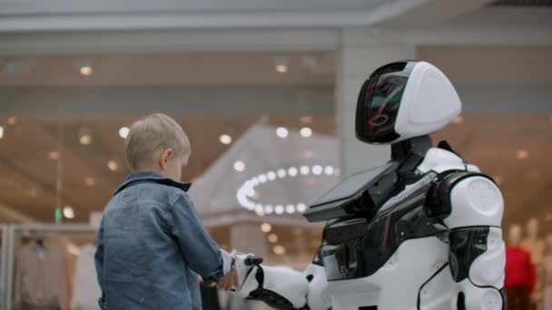 Pojken sträcker ut sin hand till roboten för ett handslag. — Stockvideo