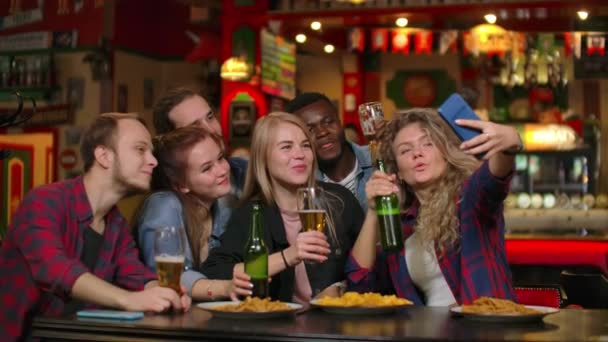 친구는 바에서 휴대 전화에서 사진을 찍고, 전화로 공유 사진을 찍습니다. 바에서 친구들과 맥주를 마시며 파티를 합니다. — 비디오