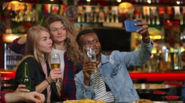 Arkadaşlar barda telefonda fotoğraf çeker, telefonda paylaşılan bir fotoğraf çekerler. Bira ile barda arkadaşlarınızla Parti