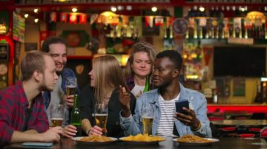 Barda büyük bir arkadaş grubu masada oturup gülerek ve sohbet bira içme