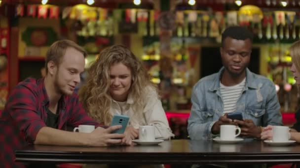 Fröhliche Gruppe von Freunden plaudert und trinkt im Stadtcafé. — Stockvideo