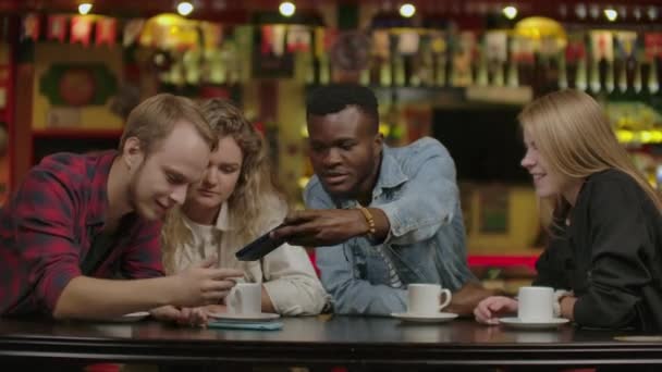 Happy multiracial young people friends talking laughing at group meeting sharing cafe table, diverse students drinking coffee having fun together enjoy multi-ethnic friendship pleasant conversation. — Stock Video