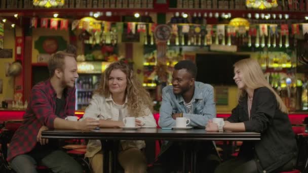 Feliz grupo de amigos charlando y tomando algo en la cafetería de la ciudad . — Vídeos de Stock