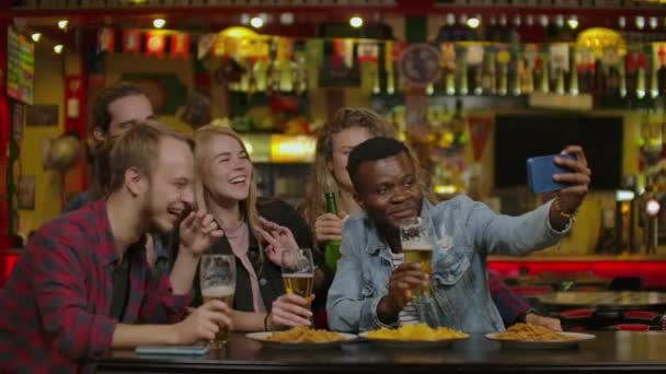 Amigos varones felices tomando selfie y bebiendo cerveza en el bar o pub. Gente, ocio, amistad, tecnología y concepto de fiesta - amigos varones felices tomando selfie . — Vídeo de stock