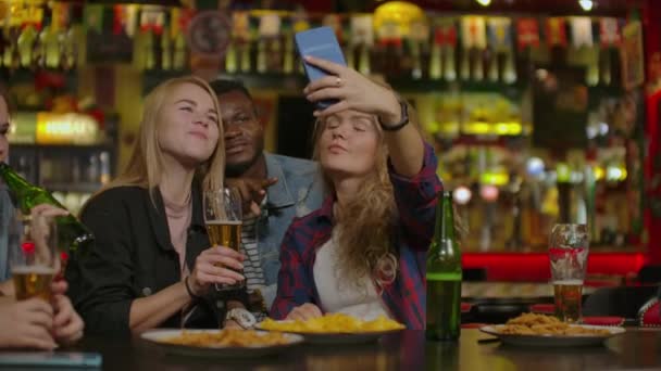 Веселая компания смотрит фото на телефон в спортивном баре . — стоковое видео