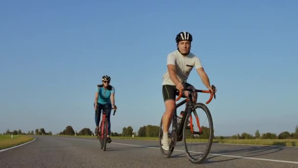 Entrenamiento difícil.Triatleta dos ciclistas Entrenamiento en bicicleta de carretera. dos ciclista montar en bicicleta de carretera en el parque de la ciudad y preparándose para Triathlon.Fit atleta entrenamiento intensivo dos hombres y mujeres ciclismo — Vídeos de Stock