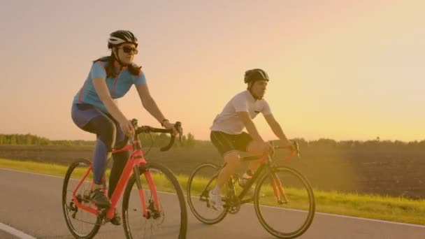 Lege ruimte. Sportieve vrienden op de fiets op de zonsondergang. Paar fietser gaan langs de kust. Sport in natuur achtergrond. Groep mensen twee Road Biker in Sunset — Stockvideo