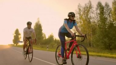 Boş alan. Gün batımında bisikletli sportif arkadaşlar. Çift bisikletçi sahil boyunca gitmek. Doğa arka planda Spor. Gün batımında iki yol bisikletçisi bir grup insan