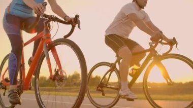 Boş alan. Gün batımında bisikletli sportif arkadaşlar. Çift bisikletçi sahil boyunca gitmek. Doğa arka planda Spor. Gün batımında iki yol bisikletçisi bir grup insan