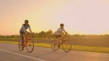 Yakışıklı erkek profesyonel bisikletçi kız arkadaşı, her iki giyiyor Koruyucu baretler birlikte sabah onun yarış bisiklet sürme sakallı ve gözlük, güneş aralarında parlıyor.
