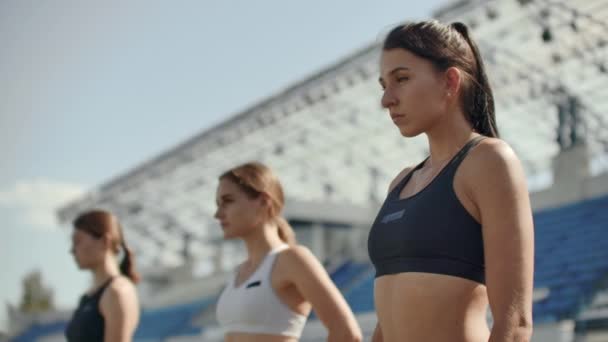 Ženské běžců v atletice sledovat, schoulil se na startovací bloky před závodem. V pomalém pohybu — Stock video