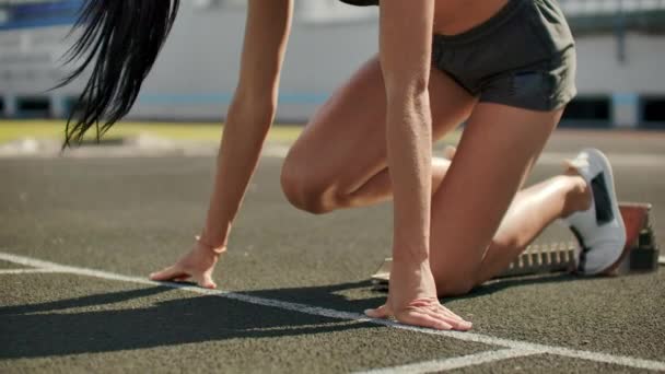 Atleta jovem e magra está em posição de começar a correr nas almofadas na pista em câmera lenta . — Vídeo de Stock