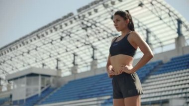 Güzel kadın atlet stadyumda nefes alıyor ve yarışa başlamaya hazırlanıyor. Yarış için motivasyon ve aton. Konsantrasyon ve tutum.
